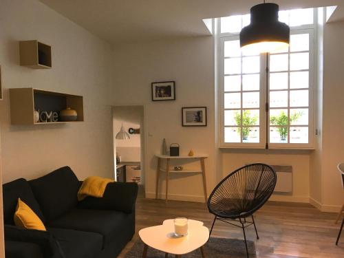 een woonkamer met een zwarte bank en een tafel bij "La Mercerie" in La Rochelle