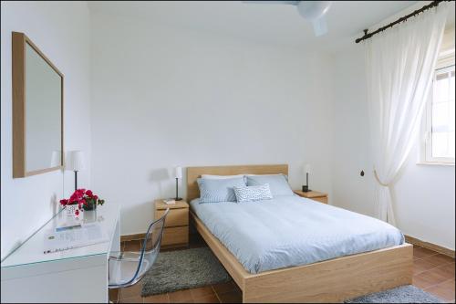 biała sypialnia z łóżkiem i lustrem w obiekcie Villa del Quarzo w Syrakuzach