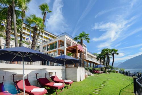 a hotel with chairs and umbrellas in front of a building at Swiss Diamond Hotel & Spa in Morcote