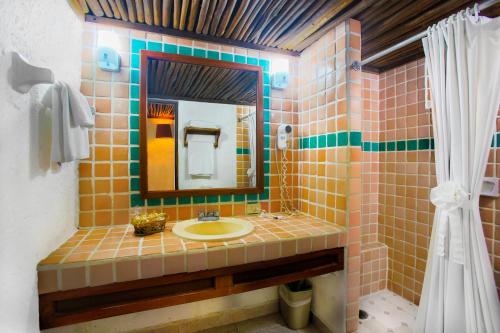 Casa del Mar Cozumel Hotel & Dive Resort في كوزوميل: حمام مع حوض ومرآة