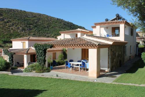 a house with a table and chairs in a yard at Residence Bouganvillage in Budoni
