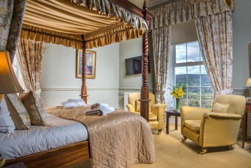 a bedroom with a canopy bed and two chairs at The Manor Hotel in Crickhowell