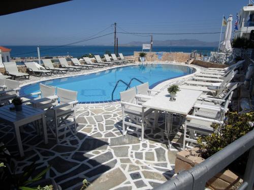 a swimming pool with white chairs and a table and chairs at The Milos in Megalochori