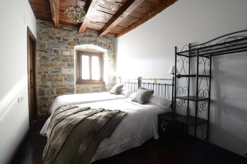 a bedroom with a white bed and a brick wall at Txantxorena in Zubiri