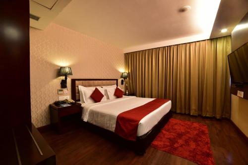 a hotel room with a bed with a red blanket at Hotel JIVA in Jamshedpur