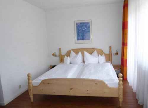 uma cama com lençóis brancos e almofadas num quarto em Rommentaler Burgstüble em Schlat