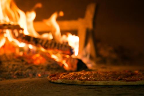 a pizza is sitting in front of a fire at Hotel Calinferno in Codognè