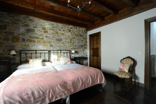 a bedroom with a large bed and a stone wall at Txantxorena in Zubiri