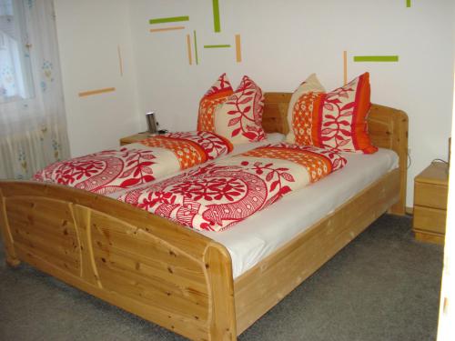 una cama de madera con almohadas rojas y naranjas. en Ferienwohnung Dieterle, en Wutöschingen