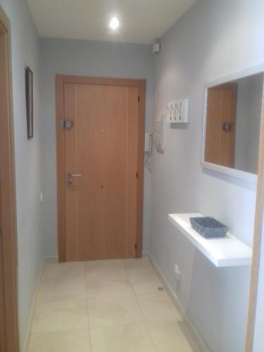 baño con puerta de madera y lavamanos en Apartamento Delfos, en Salou