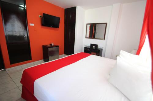 a bedroom with a white bed and an orange wall at Hotel B´liam in Tumbes