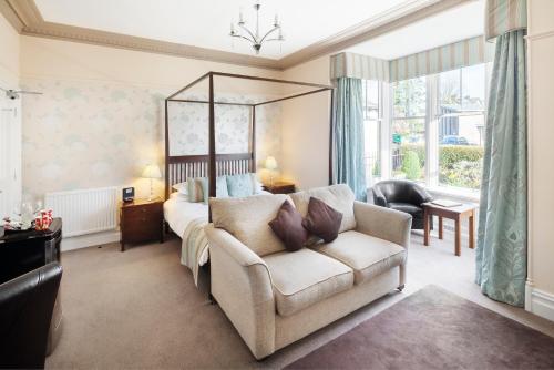 a bedroom with a bed and a couch and a chair at Hawksmoor Guest House in Windermere