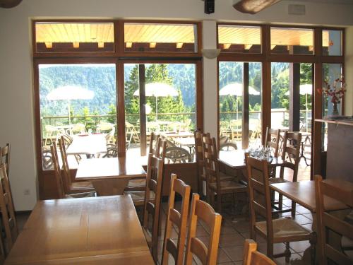 un restaurant avec des tables et des chaises en bois ainsi que des fenêtres dans l'établissement Les Terrasses du Lac Blanc - Studios & Appartements, à Orbey