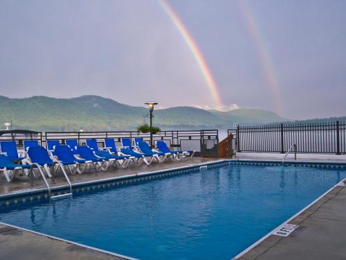 a pool with chairs and a rainbow in the background at The Lake Motel in Lake George