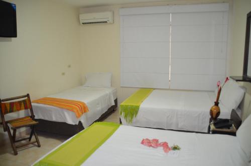 una habitación de hotel con dos camas y una silla en Hotel Casa Pablo, en Neiva
