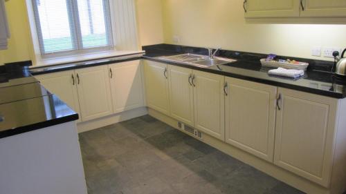 eine Küche mit weißen Schränken und einem Waschbecken in der Unterkunft Withyslade Farm in Tisbury