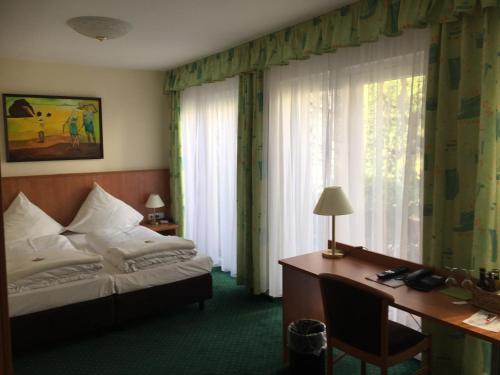 a hotel room with a bed, desk, lamp and window at Frick's Hotel & Restaurant in Hannover