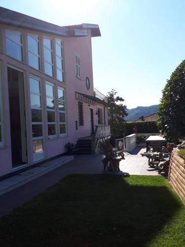 a pink house with a grass yard and a building at Casa Rea in Beverino