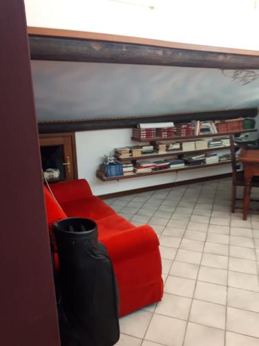 a red couch in a room with a shelf of books at Casa Rea in Beverino