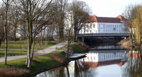 a bridge over a river next to a building at Andersen Hotel Birkenwerder in Birkenwerder
