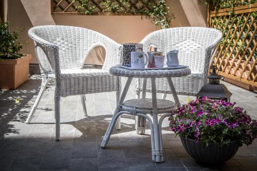 Dos sillas de mimbre y una mesa con tazas y tazas. en La Piazzetta delle Regine, en Roma