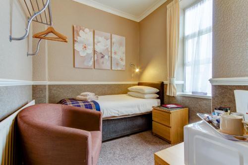 a small room with a bed and a chair at New Brooklyn in Blackpool