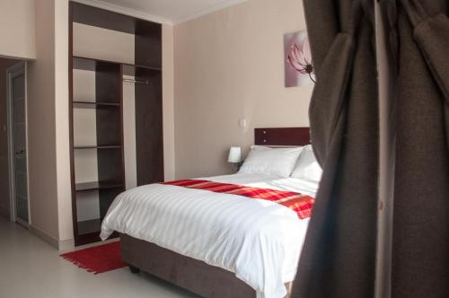 a bedroom with a bed with a red and white blanket at Bannerloft Guest house in Gaborone
