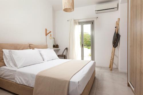 a white bedroom with a bed and a window at Villa Vinea Santorini in Imerovigli