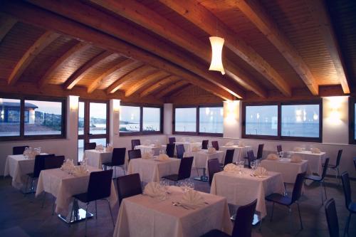 um salão de banquetes com mesas e cadeiras brancas e janelas em Forte Hotel em Vieste