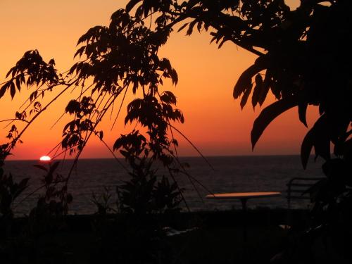 a sunset over the ocean with a table at Palmina Mare Villa and Studios in Paralia Vrachou