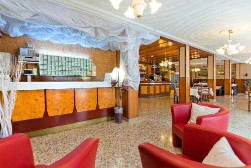 un vestíbulo con sillas rojas y un bar en Hotel Bianchi, en Bibione