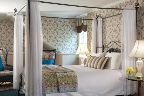 a bedroom with a canopy bed and a chair at Rabbit Hill Inn in Lower Waterford