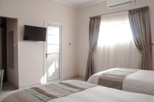 a hotel room with two beds and a window at Bannerloft Guest house in Gaborone