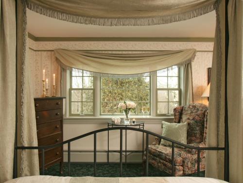 a bedroom with a bed and a chair and a window at Rabbit Hill Inn in Lower Waterford