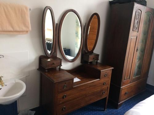 a bathroom with three mirrors on top of a dresser at Staigue Fort House in Caherdaniel