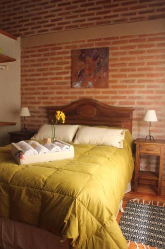 a bedroom with a yellow bed with a brick wall at Refugio Del Guira Guira in Los Reartes