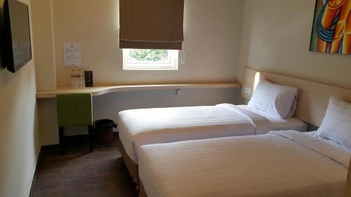 two beds in a small room with a window at BIZ HOTEL City Center in Ambon