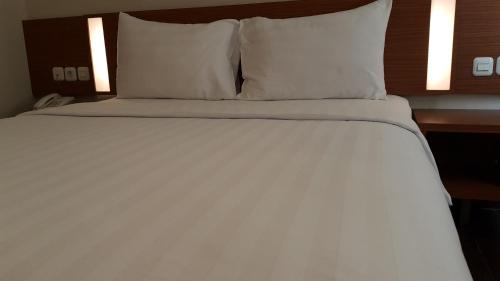 a bed with white sheets and pillows in a room at BIZ HOTEL City Center in Ambon