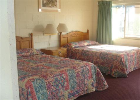 a hotel room with two beds and a window at Village Inn in Tulare