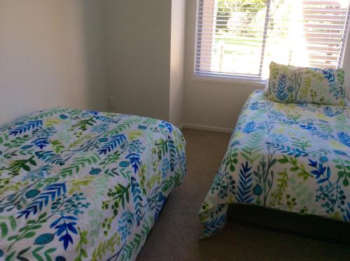 1 dormitorio con 2 camas y ventana en Bethlehem Garden Retreat, en Tauranga