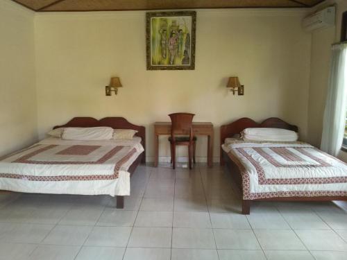 two beds in a room with a table and a chair at Indraprastha Ubud Home Stay in Ubud