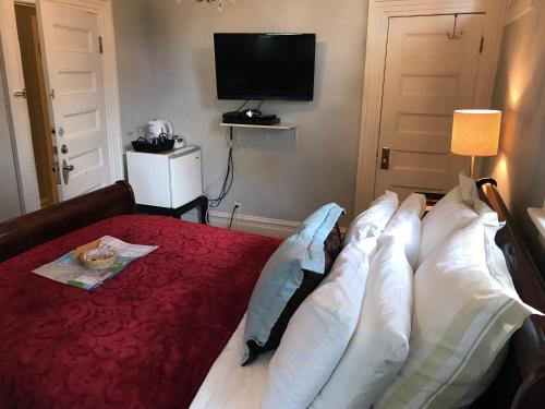 a bedroom with a bed with pillows and a television at Barclay House Bed and Breakfast in Vancouver