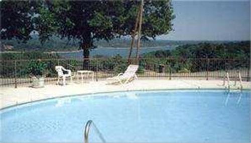 a swimming pool with two chairs and a tree at Beaver Lake Lodge in Rogers
