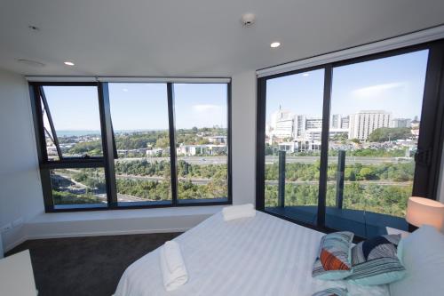 a bedroom with a bed and large windows at Fantastic 2 Bedroom Apartment with Sea Views in Auckland