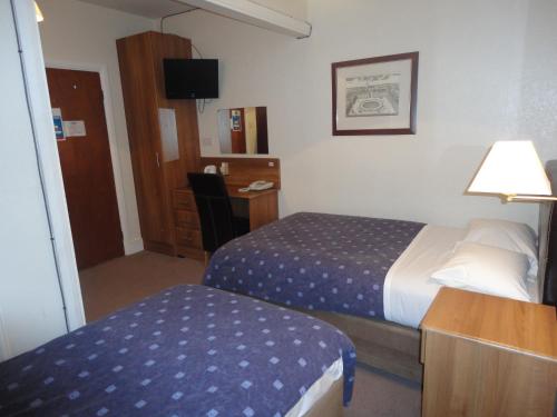 a hotel room with a bed and a desk with a lamp at Warwick Lodge in Kingston upon Thames