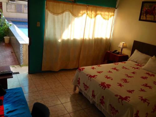 a bedroom with a bed with a white comforter and a window at Hotel MundialCity in Guayaquil