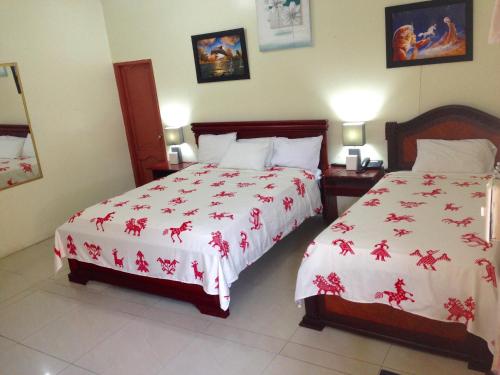 a bedroom with two beds with red and white sheets at Hotel MundialCity in Guayaquil