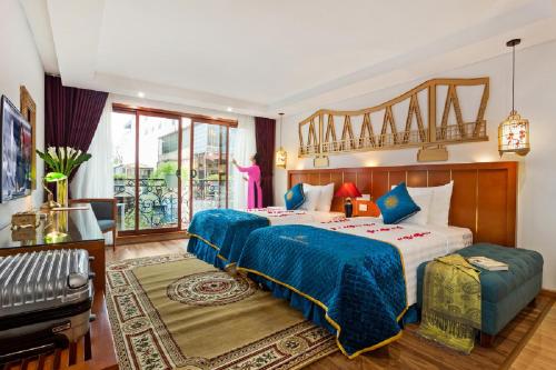 um quarto com uma cama grande e lençóis azuis em Hanoi Golden Holiday Hotel em Hanói