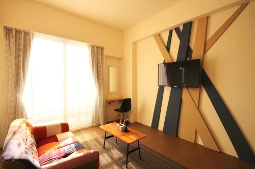 a living room with a couch and a tv on the wall at 艾希兒民宿 I'm Here hostel l小家庭包棟首選l 台東包棟 l台東火車站l背包單人 in Taitung City