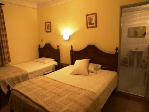a hotel room with two beds and a sink at Estrela in Manteigas